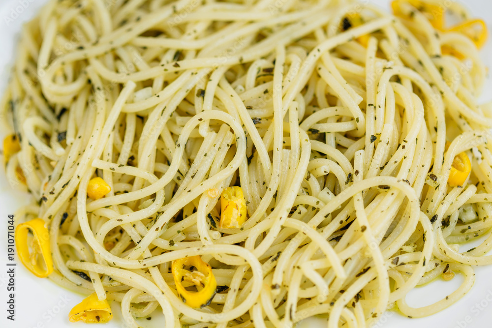 Macro photo of Tasty pasta with yellow chili pepper, garlic and dried basil on white plate. Macro photo of Tasty pasta with yellow chili pepper, garlic and dried basil on white plate.