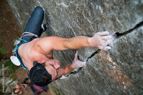 Shirtless man rock climbing a thin splitting crack in Squamish