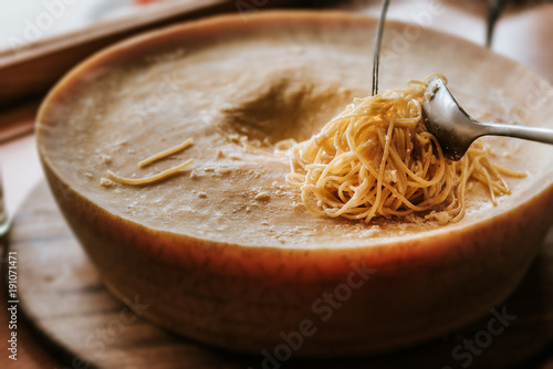 Spaghetti pasta preparation in a parmesan cheese wheel. photo