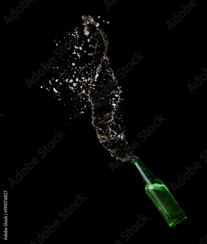 Green beer bottle opening with exploding and splashing on dark background