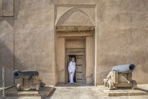 arab man in traditional omani outfit in an old castle photo