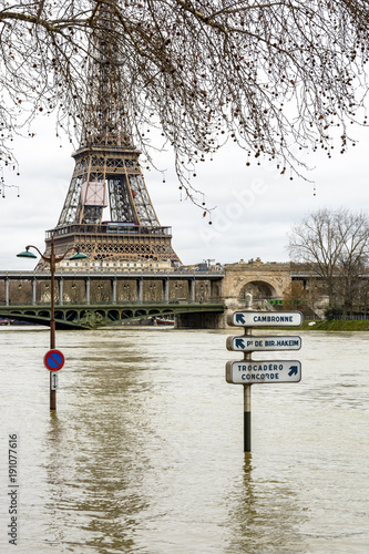 The swollen Seine during the winter flooding episode of January 2018, with half immersed road signs and street lights in the foreground and the Eiffel tower and Bir-Hakeim bridge in the background. photo