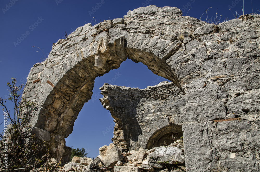 Ruins of the ancient city of Sidima, Turkey, a wall with a partially preserved arch against a blue sky