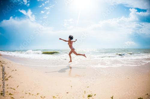 A girl is jumping on the beach.
