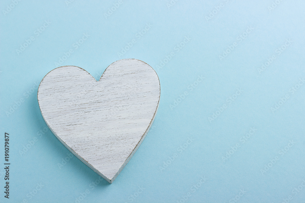 Obraz premium White wooden heart on blue cardboard background.
