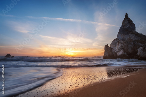 beautiful Atlantic ocean view horizon with sandy beach,  rocks and waves at sunset.  Sintra,  Portugal