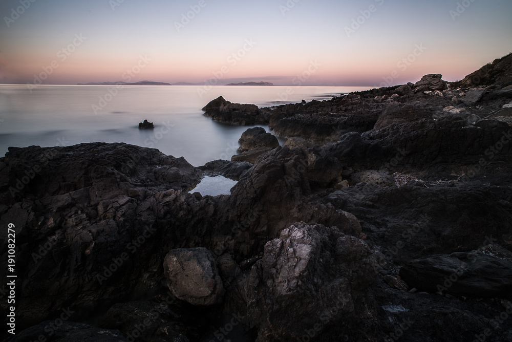spiaggia con rocce laviche e mare al tramonto