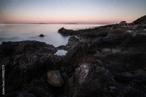 spiaggia con rocce laviche e mare al tramonto