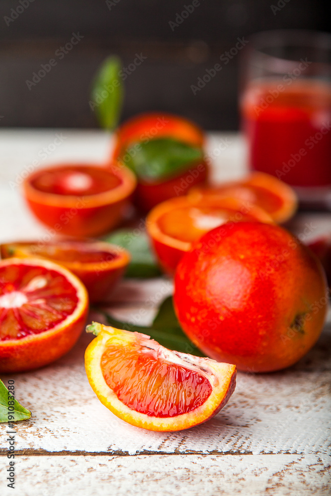 Bloody red oranges slices with leaves on wooden background Bloody red oranges slices with leaves on wooden background