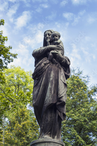 Old statue of Virgin Mary with baby on cemetery