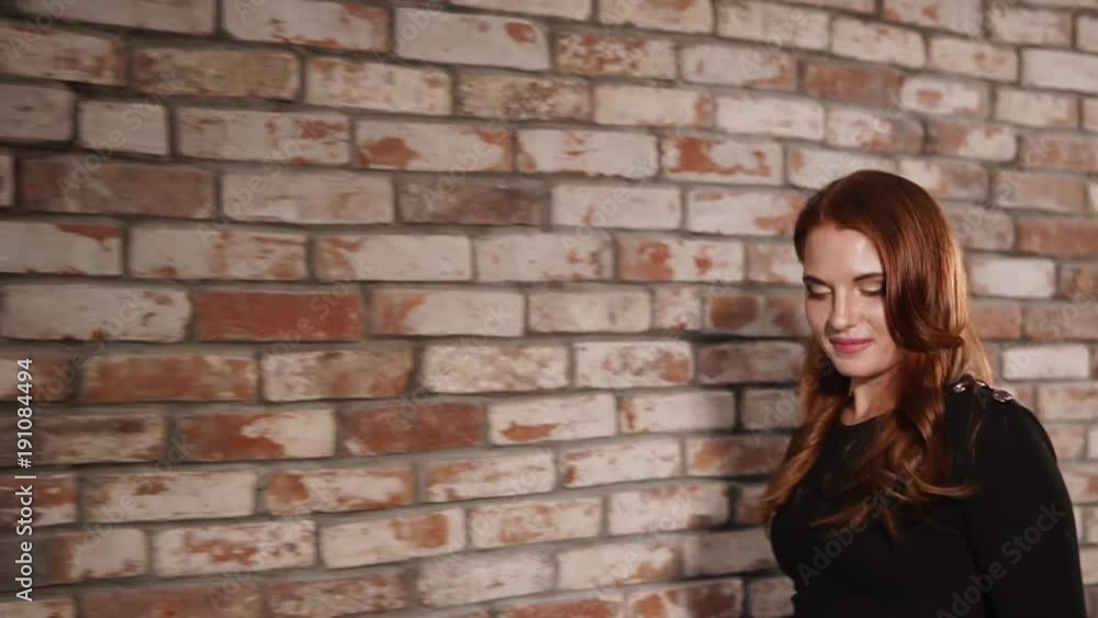 Incredible female model is walking by the brick wall in the studio. She is smiling and lookign very happy. Incredible female model is walking by the brick wall in the studio. She is smiling and lookign very happy.