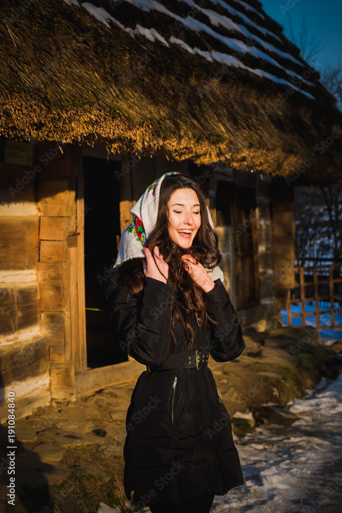 Obraz premium Happy girl stands in the courtyard near a wooden house