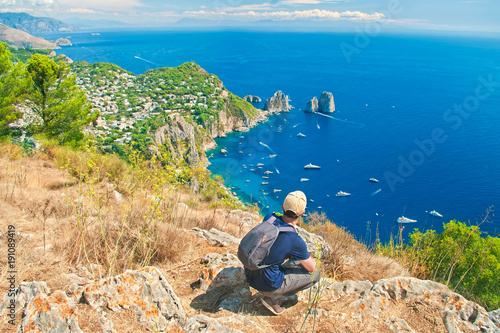 young man resting on top of mountain with sea vew