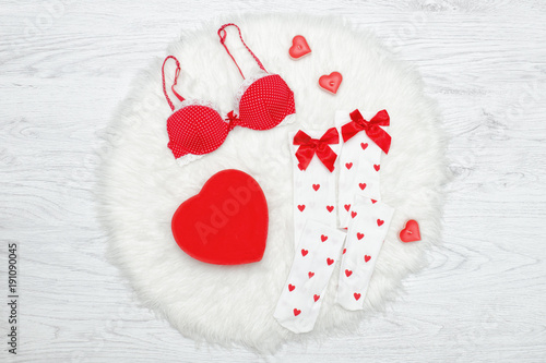 Fashion concept. Red bra, white stockings and box in the shape of heart. White fur