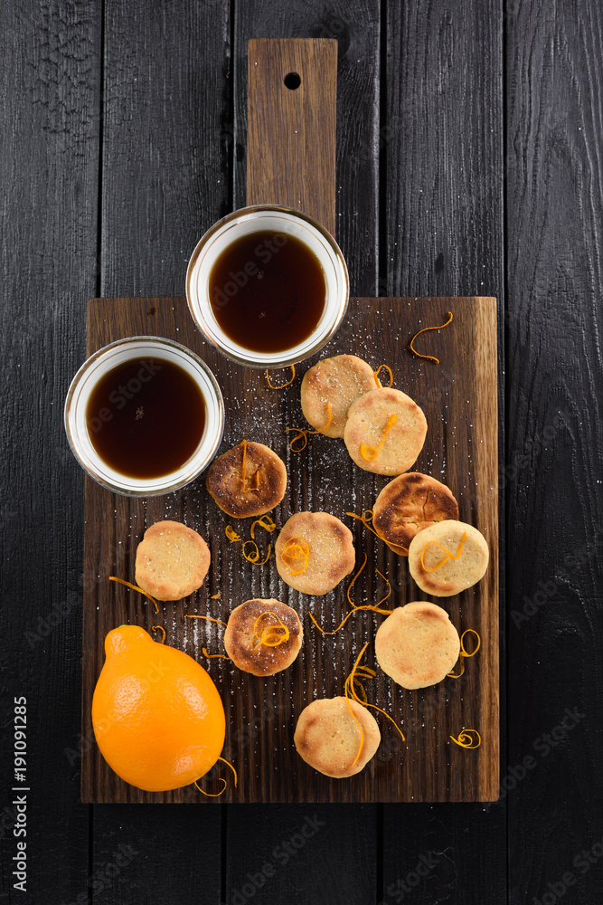Homemade lemon cookies served on oak board with organic lemon and black tea above view Homemade lemon cookies served on oak board with organic lemon and black tea above view