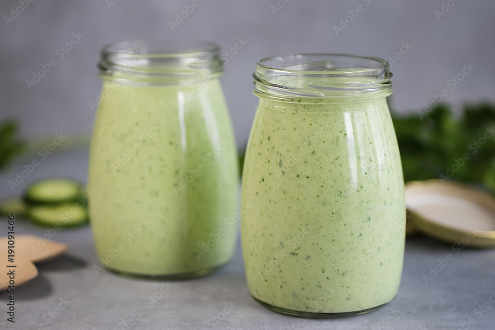Green organic smoothies in glass jars on a gray background. Green organic smoothies in glass jars on a gray background.