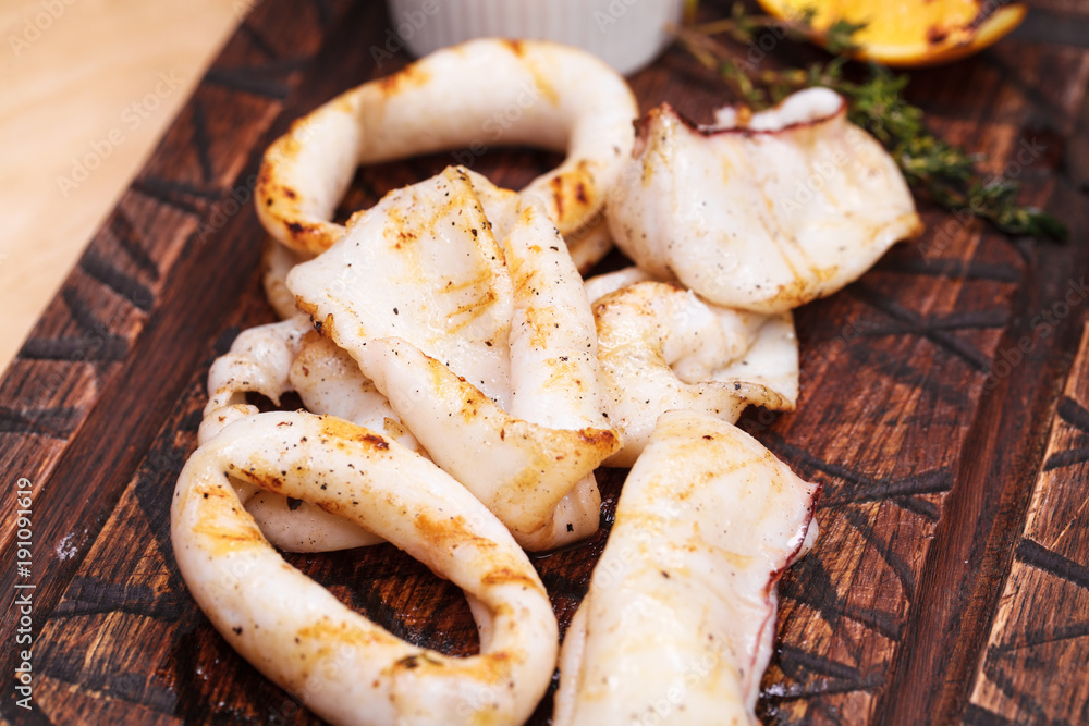 grilled squid rings on a wooden board with sauce grilled squid rings on a wooden board with sauce