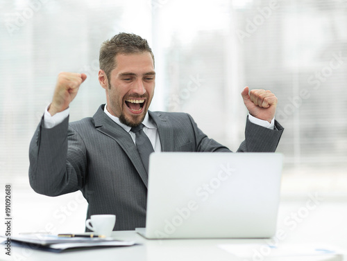 closeup.happy businessman sitting in front of an open laptop.