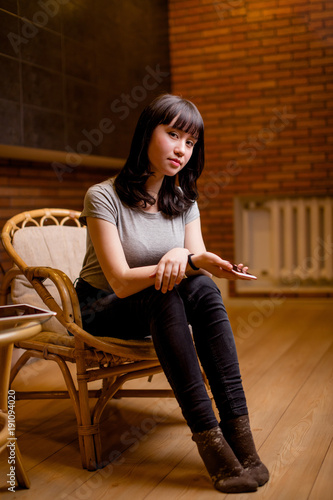 Asian woman smiling to camera near brick wall photo