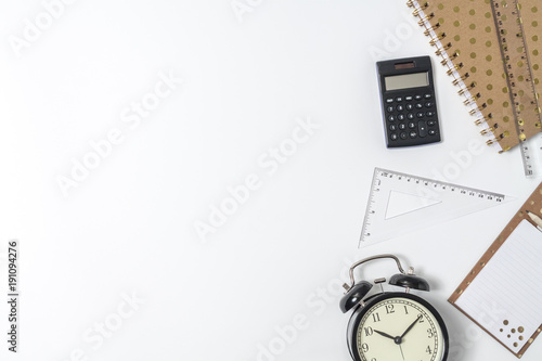 Top view on white empty desk with space for text, notebook with polka dot, black clock, calculator, ruler and set square
