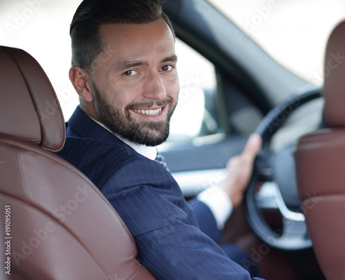 businessman sitting at the wheel of a car and looking at the camera
