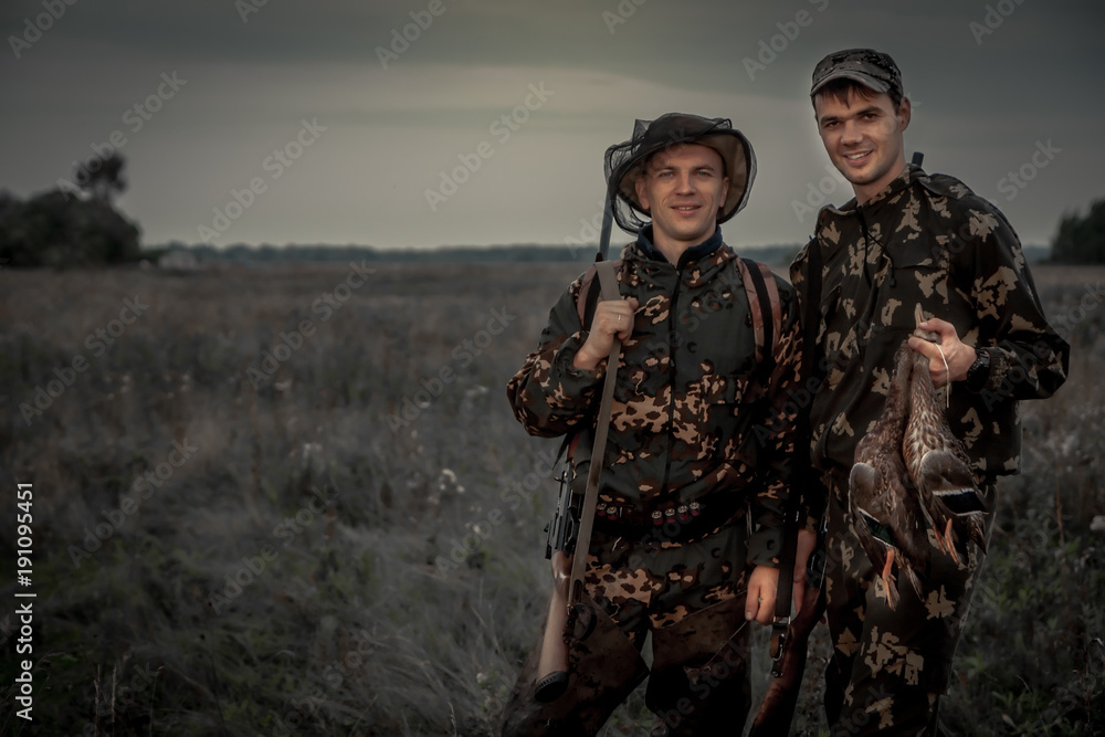 Hunters men with trophy in rural field during hunting period at dusk Hunters men with trophy in rural field during hunting period at dusk