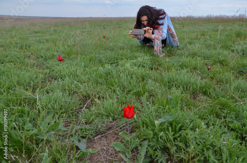 young woman taking photo of wild red tulips lake Manych-Gudilo, Kalmykia © ssmalomuzh