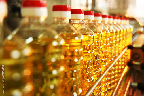 line or conveyor for food production of sunflower oil. Bottles with vegetable oil close-up against the background of factory equipment