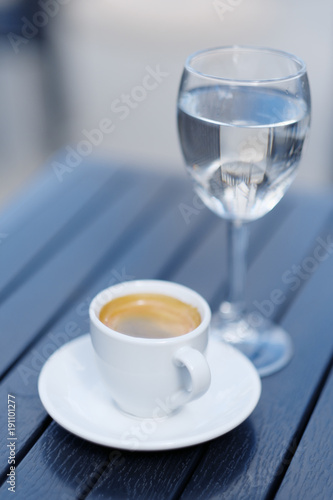 White cup of coffee and glass of water place on wood table