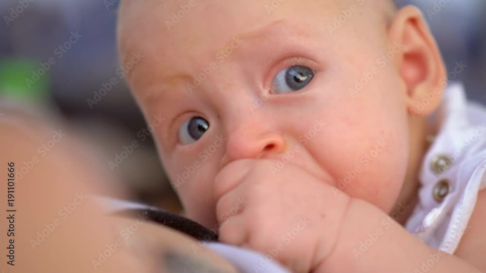 Close-up shot of a blue-eyed three months baby girl with hand in the mouth Close-up shot of a blue-eyed three months baby girl with hand in the mouth
