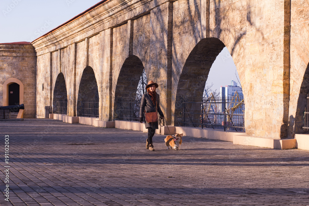 young woman in hat in  park walk with cute corgi dog, sunny autumn day 