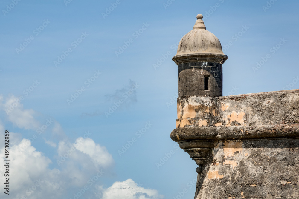 The outer tower and wall with sentry box of San Felipe del Morro fort in old San Juan in Puerto Rico, USA against the blue sky with clouds and copy space