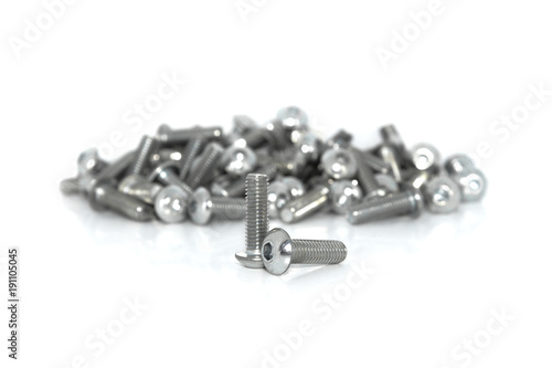 A couple of isolated galvanized industrial steel screws in front of blurt pile on white background