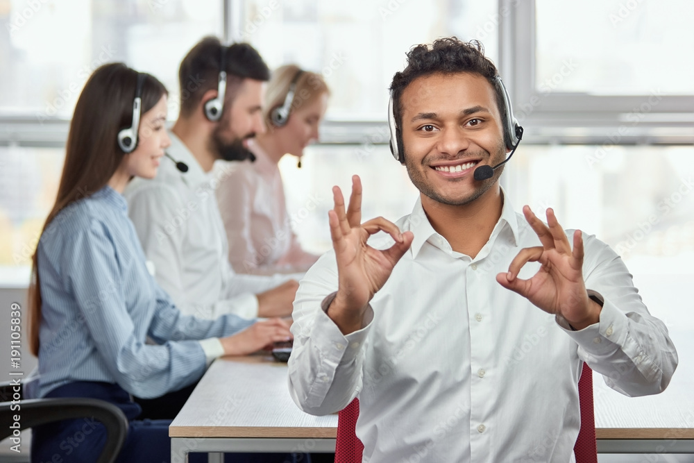 Happy call centre worker giving ok gestures. Portrait of handsome indian black man makes all right, OK, sign using both hands. Everything is fine. Happy call centre worker giving ok gestures. Portrait of handsome indian black man makes all right, OK, sign using both hands. Everything is fine.