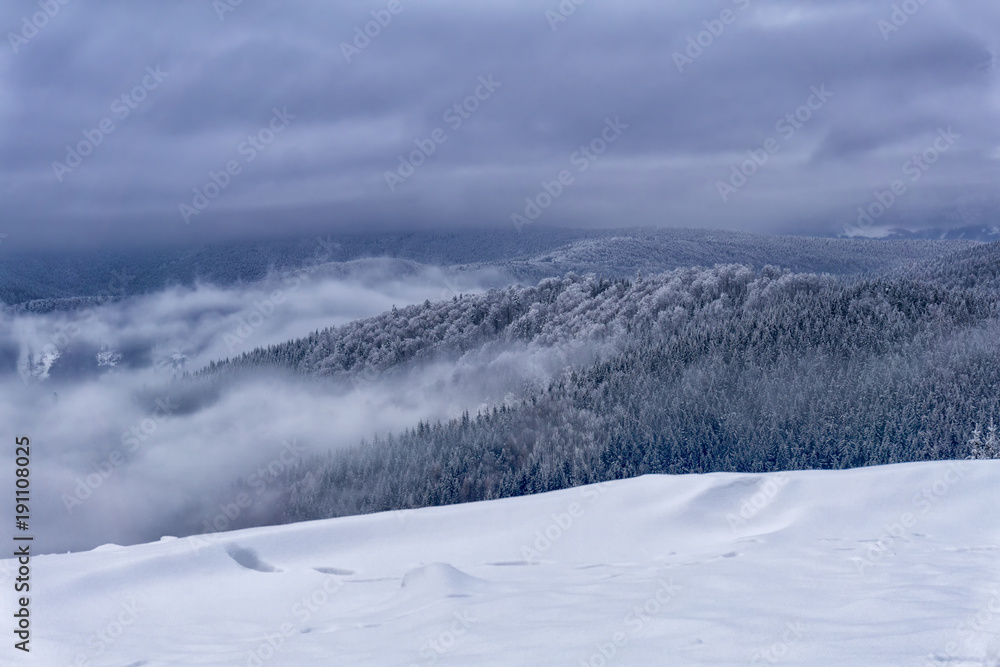 Winter foggy mountain landscape. Fairytale  evening or afternoon with dramatic clouds in the sky