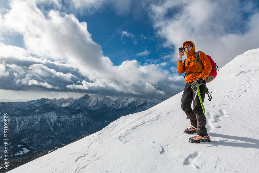 Mountaineer photographing on the snowy slope of the Dovska Baba mountain in Karavanke range, Slovenia 