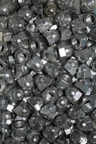 Lots of galvanized industrial steel cap nuts on a white background