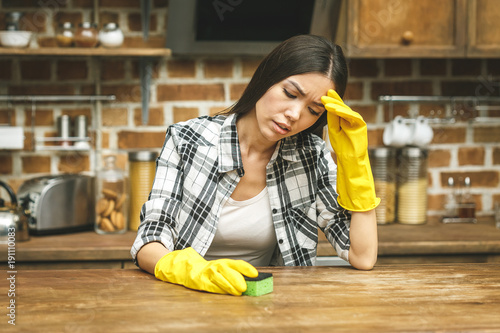 Beautiful woman in the kitchen is cleaning her house, close-up. In stress.
