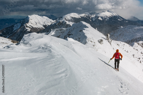 Mountaineer walking on the snowy slope of the Dovska Baba mountain in Karavanke range, Slovenia 