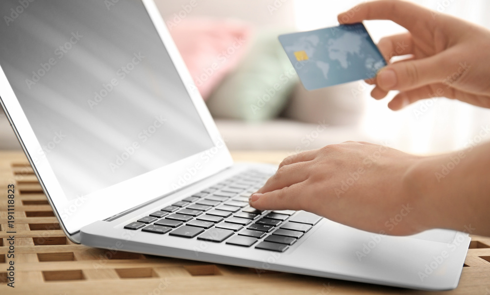 Woman holding credit card while using laptop, closeup. Internet shopping concept Woman holding credit card while using laptop, closeup. Internet shopping concept