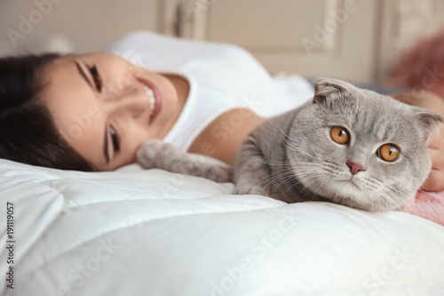 Young woman with cute pet cat on bed at home