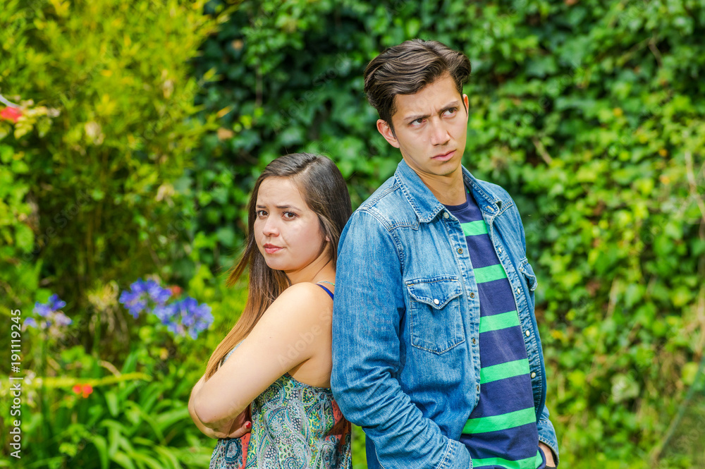 Close up of young man and beautiful woman back to back both with mad face, friend zone concept Close up of young man and beautiful woman back to back both with mad face, friend zone concept