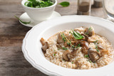 Plate with delicious risotto and mushrooms on table