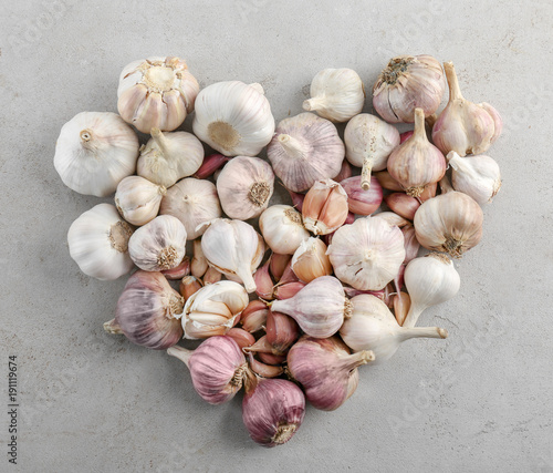 Heart shape of fresh garlic heads on grey background