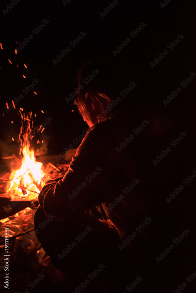 Man sitting in front of campfire at night Stock Photo | Adobe Stock