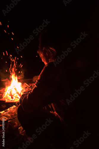 Man sitting in front of campfire at night