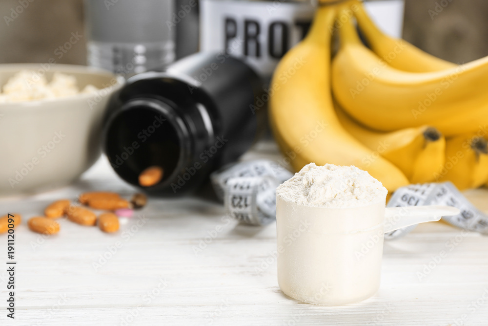 Scoop with protein powder and products on table Scoop with protein powder and products on table