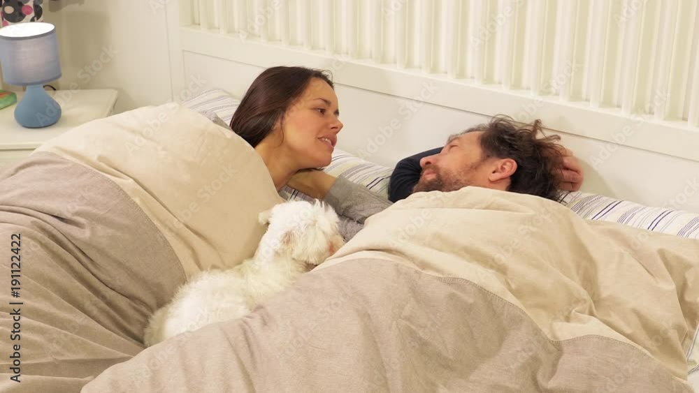 Woman cuddling husband and dog in bed happy closeup Woman cuddling husband and dog in bed happy closeup