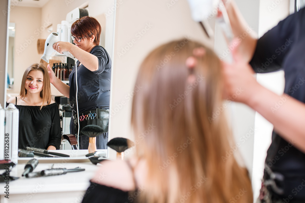 Hairdresser dries hair with a hairdryer in beauty salon Hairdresser dries hair with a hairdryer in beauty salon