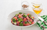 Broccoli salad / Broccoli, pomegranate, grapefruit salad with walnut, red onion, honey and olive oil in porcelain bowl on white wooden background